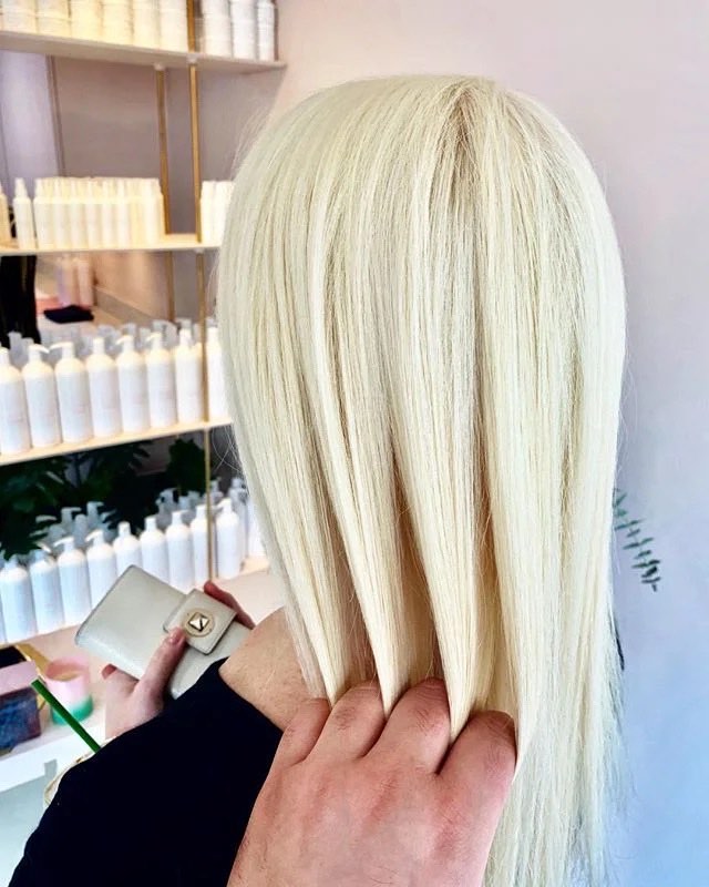 NAZNAZ Salon: blonde colour result with product shelves behind. Photo from their website.