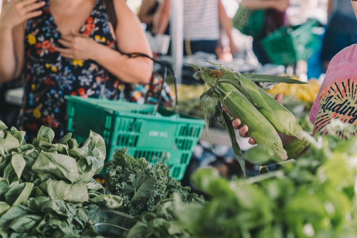 Riverview Farmers Market: a shopper picking corn over kale and greens. Photo from their website.